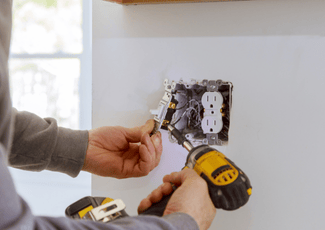 A drill being used to install a light switch and plug-in