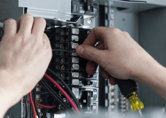 an electrical panel open with someone working on it with a screwdriver